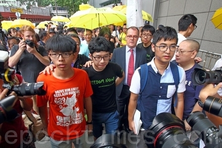 香港警察本部に出頭する3人（左から黄之鋒、羅冠聡、周永康）。支援者百人あまりが駆けつけた　（大紀元）
