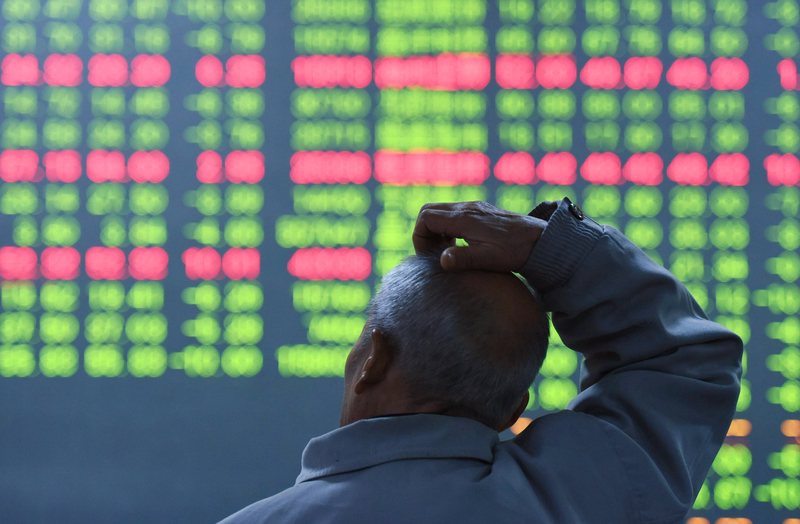 株式情報を示す電光掲示板の前に座る個人投資家（CHINA OUT / AFP / STR）